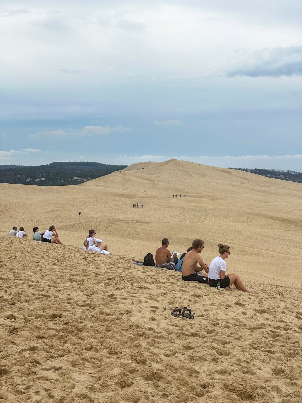 Menschen sitzen auf einer riesigen Düne