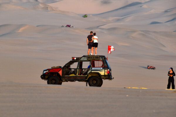 Peru: Toursiten posieren in der Dünenlandschaft der Oase Huacachina