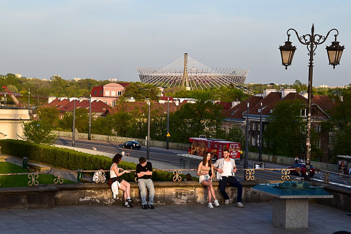 Menschen auf einem Platz mit Blick auf ein modernes Fußballstadion
