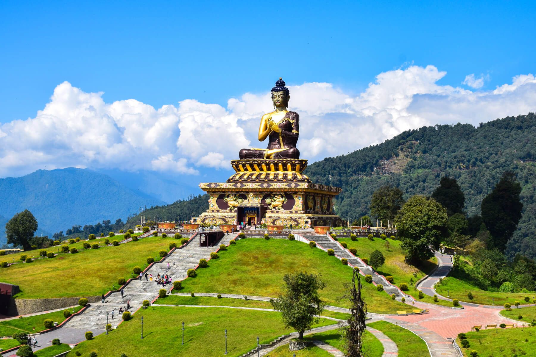 Reise nach Sikkim: Die Chenrezig-Statue bei Pelling sitzt auf einem Podest inmitten einer grünen Landschaft