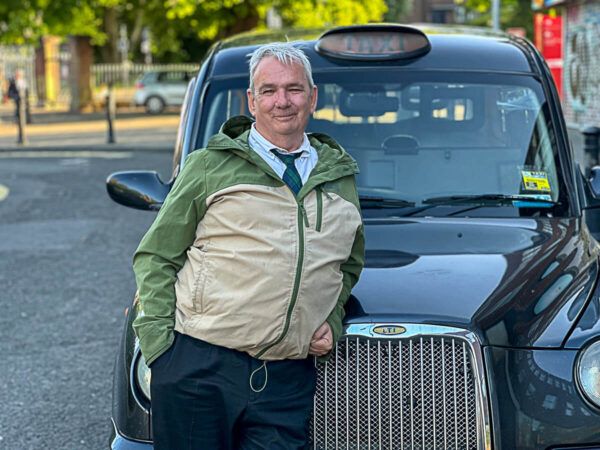 Sehenswürdigkeiten Belfast: ein Taxifahrer vor seinem schwarzen Taxi
