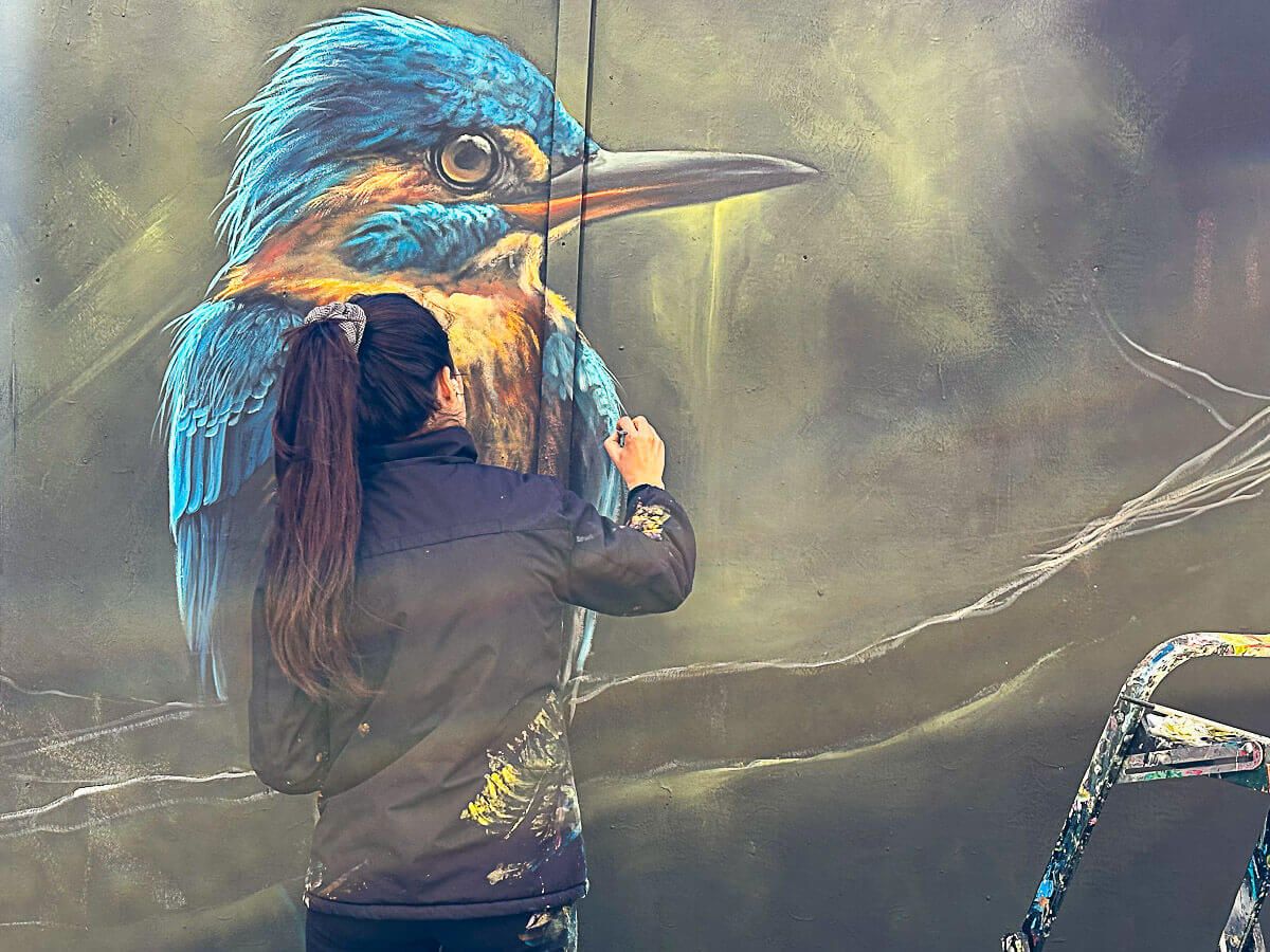 Street Art Künstlerin malt einen Eisvogel