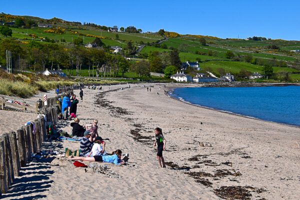langer Sandstrand, an dem einige Urlauber sitzen