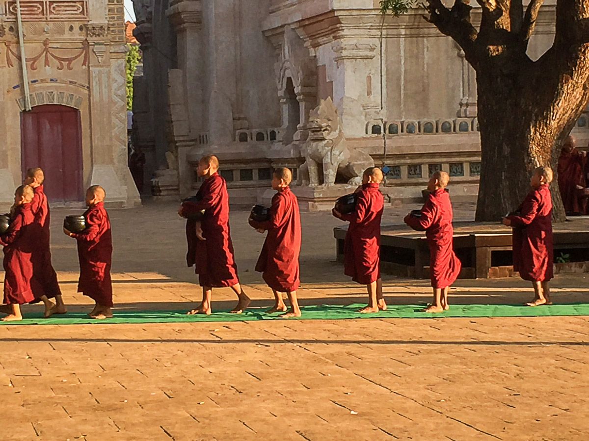 Mönche beim täglichen Almosengang vor einem Tempel