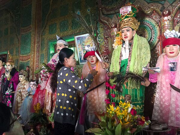 Frau verehrt Schutzgeister in bunten Kostümen in Mount Popa, Myanmar