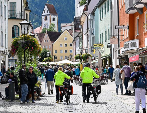Menschen drängen sich in der Haupteinkaufsstraße von Füssen. Im Hintergrund das Hohe Schloss.
