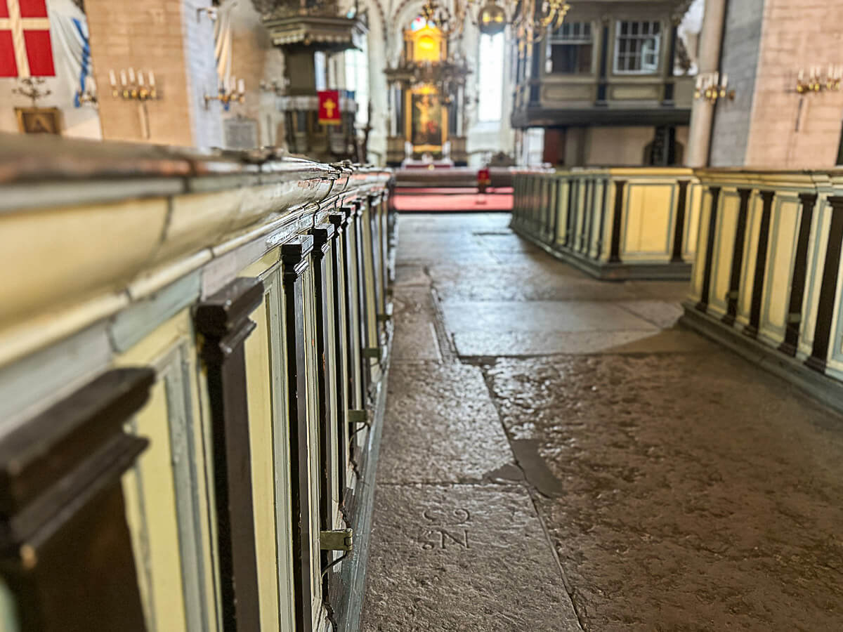 Blick ins Innere einer mittelalterlichen Kirche mit Kirchenbänken im Vordergrund