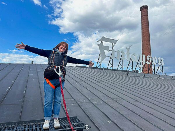 Mit dem Zug durch Finnland: Helsinki – Turku – Tampere 75 Tampere: angeseilte Frau auf dem Dach eines Industriegebäudes mit Schornstein aus Backstein
