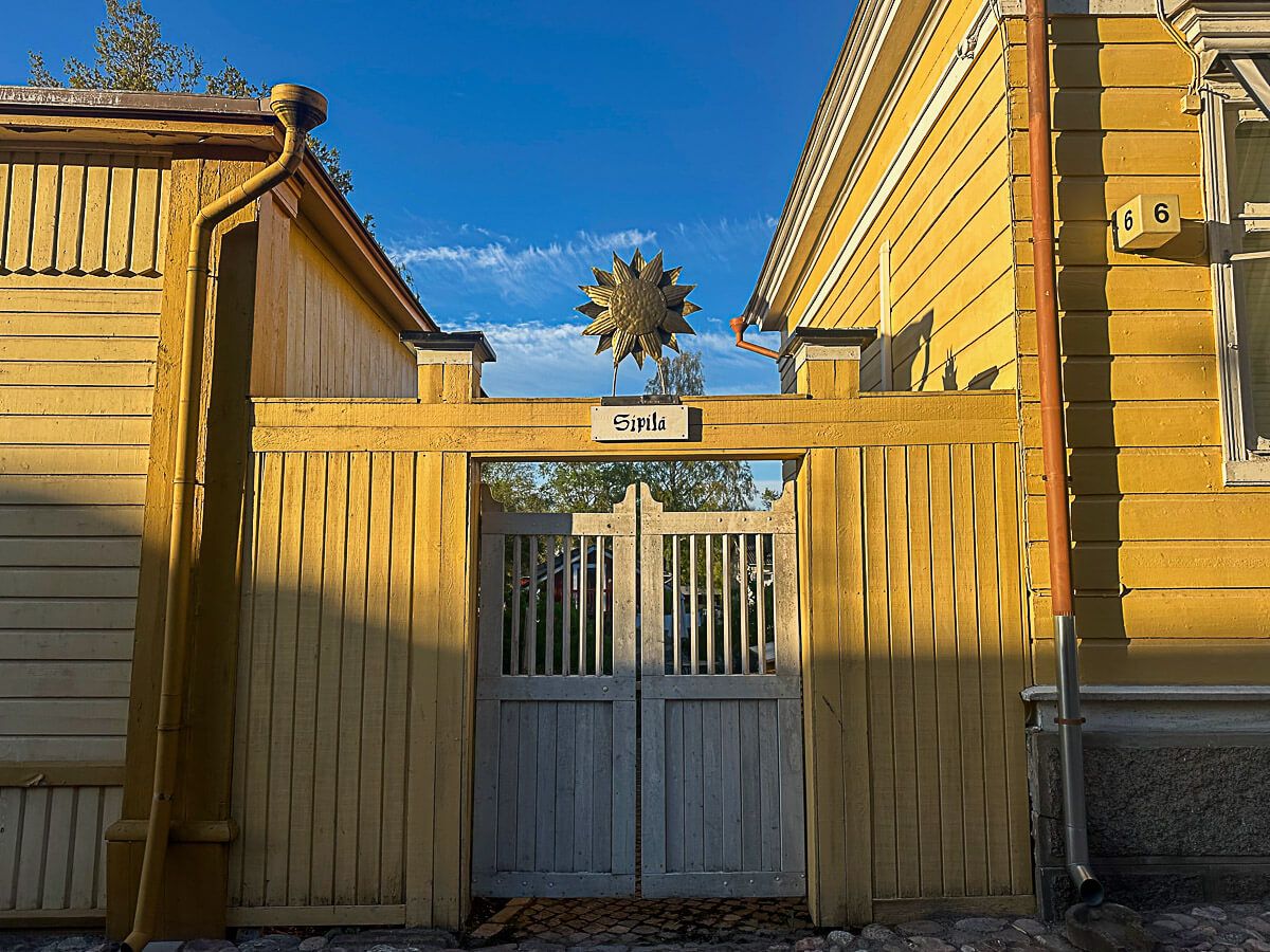 Mit dem Zug durch Finnland: Helsinki – Turku – Tampere 60 Naantali: gelbe Holzhäuser und eine Sonnensymbol über einem Eingang