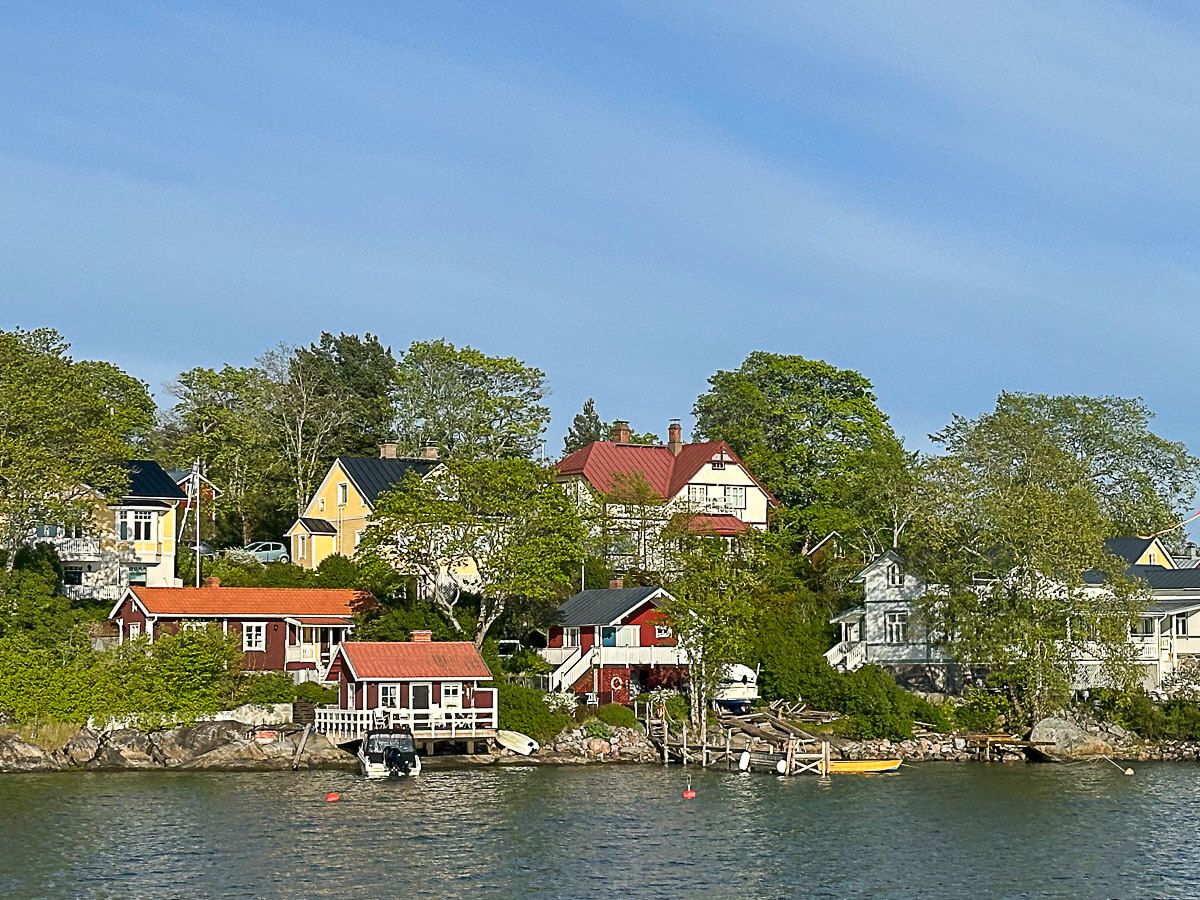 Mit dem Zug durch Finnland: Helsinki – Turku – Tampere 56 Turku, Schärengarten: Blick vom Schiff auf eine Siedlung mit bunten Holzhäusern auf einer Schäreninsel