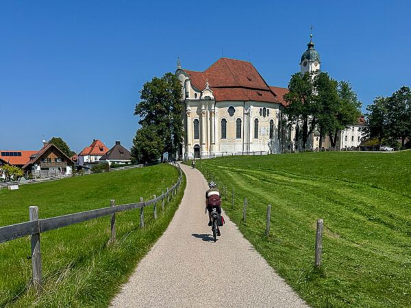 Radfahrer fährt auf die Wieskirche zu.