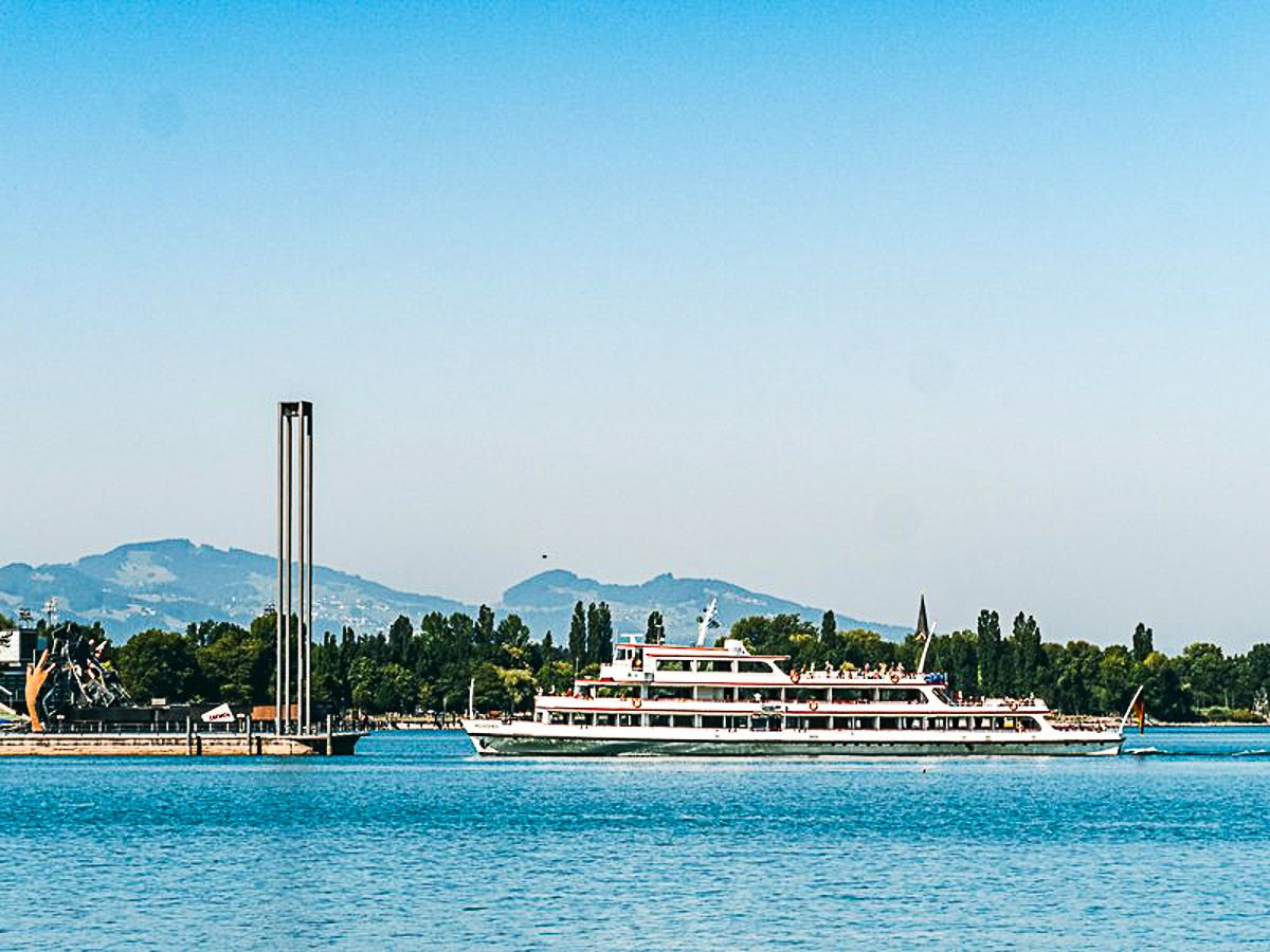 Dampfer steuert auf den Hafen von Bregenz zu. Im Hintergrund die Alpen.