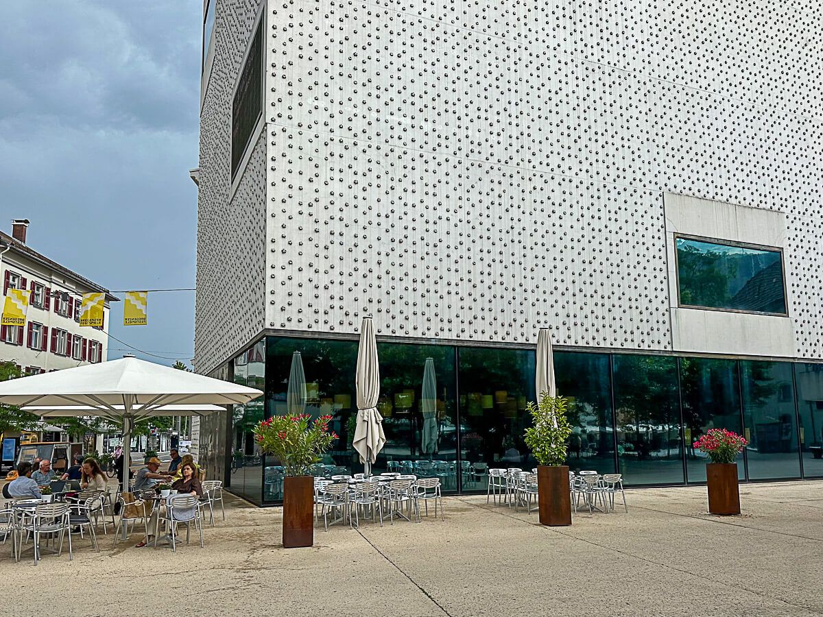 Museum mit moderner Fassade, davor ein Café