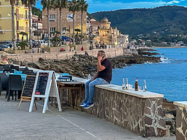 Mann auf einer Mauer am Meer 