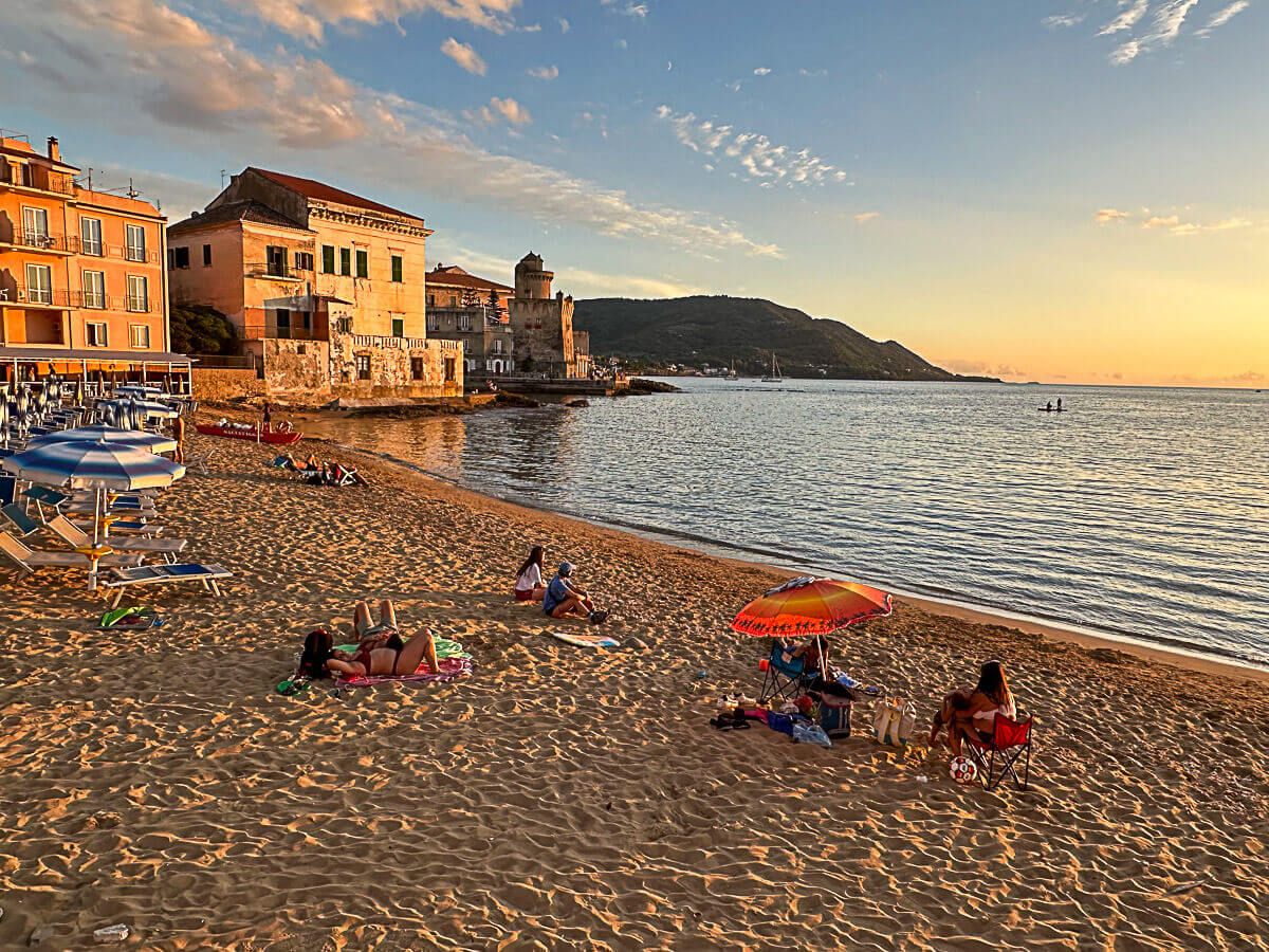 Strand mit wenigen Badegästen bei Sonnenuntergang