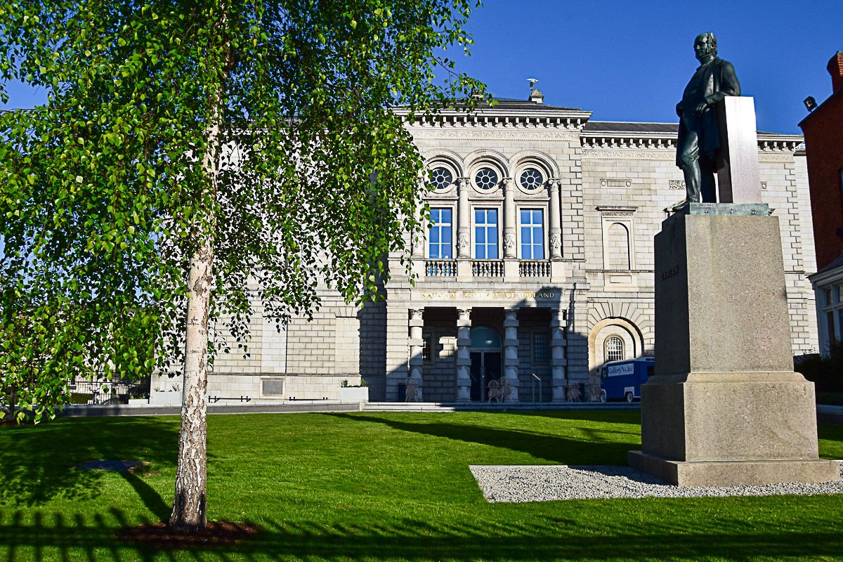 Repräsentatives Gebäude aus dem 19. Jahrhundert mit einem Denkmal davor