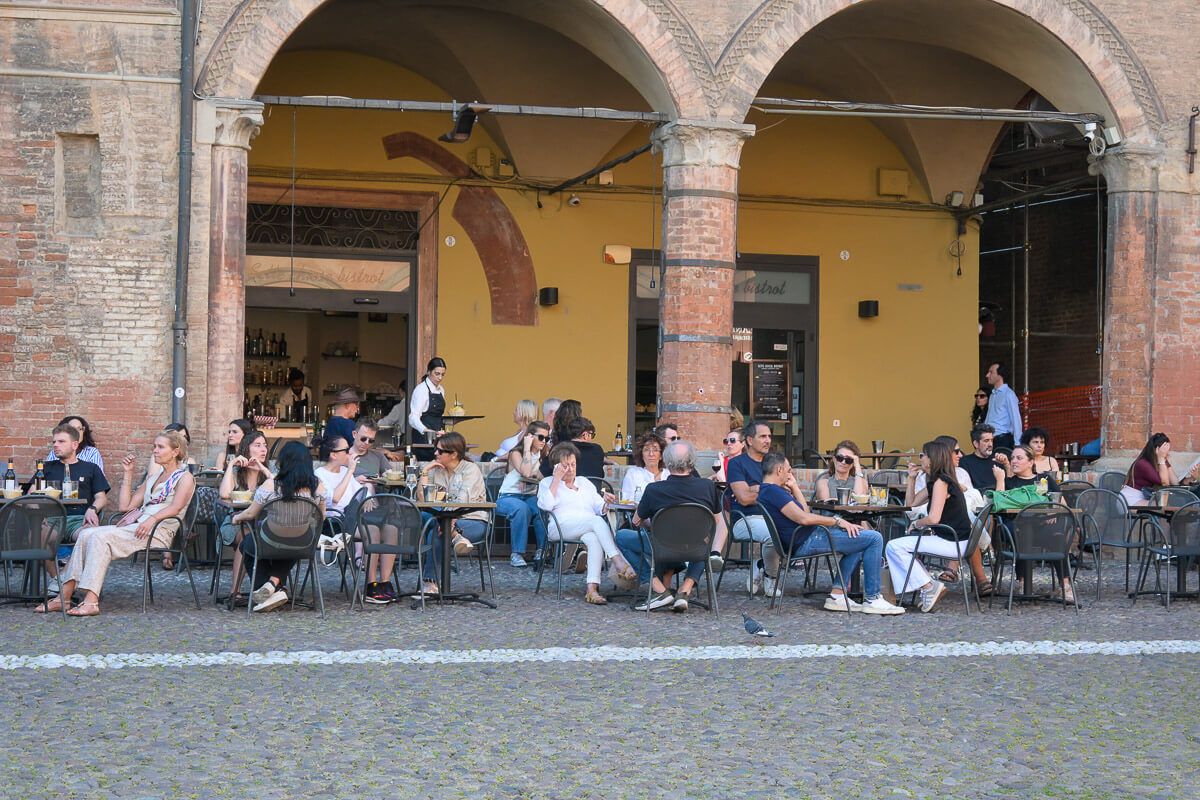 Zwei Stadtperlen der Emilia-Romagna: Sehenswürdigkeiten in Bologna und Ravenna auf der Durchreise 10 Sehenswürdigkeiten in Bologna auf der Durchreise: Menschen sitzen in einer Bar unter Arkaden