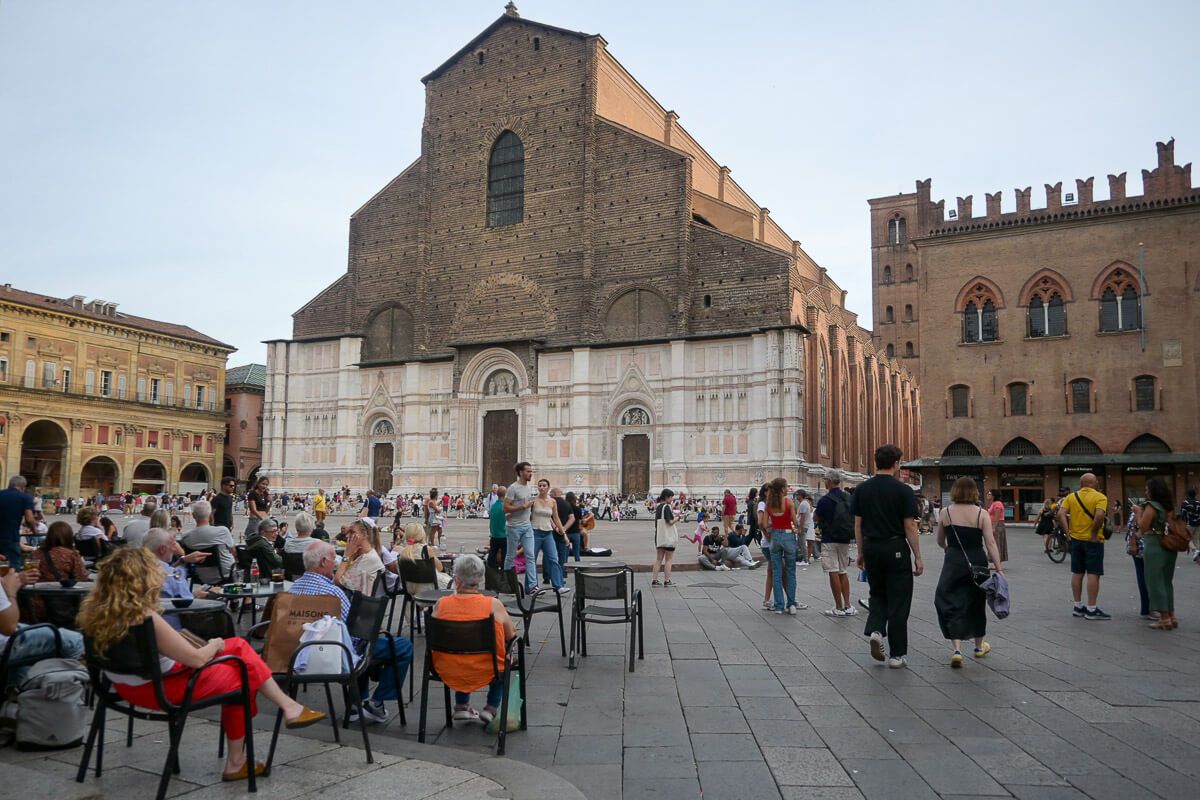 Zwei Stadtperlen der Emilia-Romagna: Sehenswürdigkeiten in Bologna und Ravenna auf der Durchreise 11 Kirche an einem großen Platz. Davor ein Café mit vielen Gästen