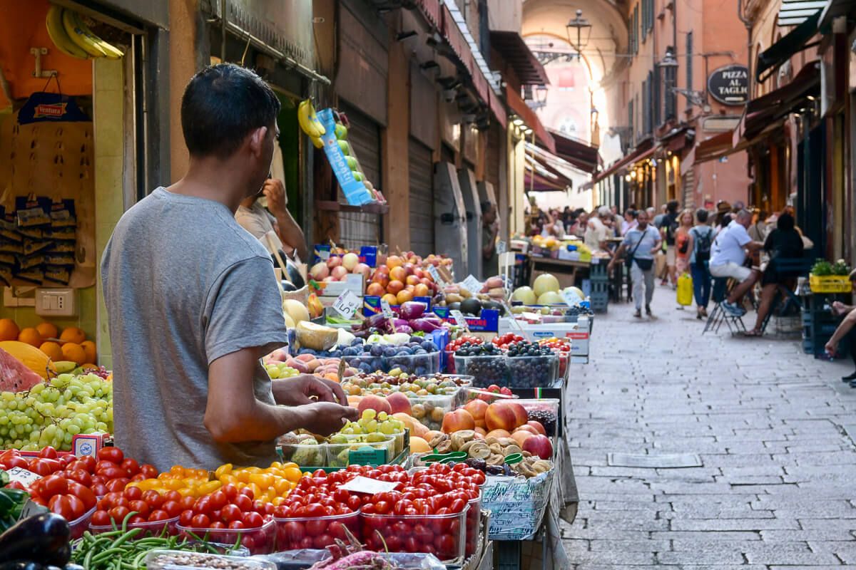 Zwei Stadtperlen der Emilia-Romagna: Sehenswürdigkeiten in Bologna und Ravenna auf der Durchreise 9 Sehenswürdigkeiten in Bologna auf der Durchreise: Verkäufer an einem Stand mit Obst und Gemüse in Bologna