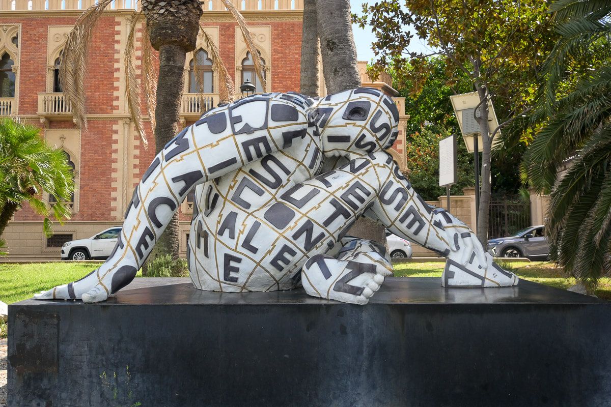 Moderne Skulptur einer Frau auf einem Podest vor einem Palazzo