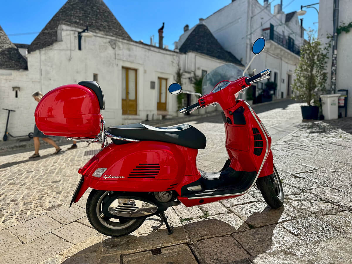 Rote Vespa inmitten einer weißen Stadt