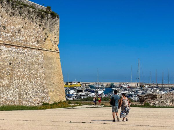Bastion der Stadtmauer von Otranto am Hafen und zwei Spaziergänger