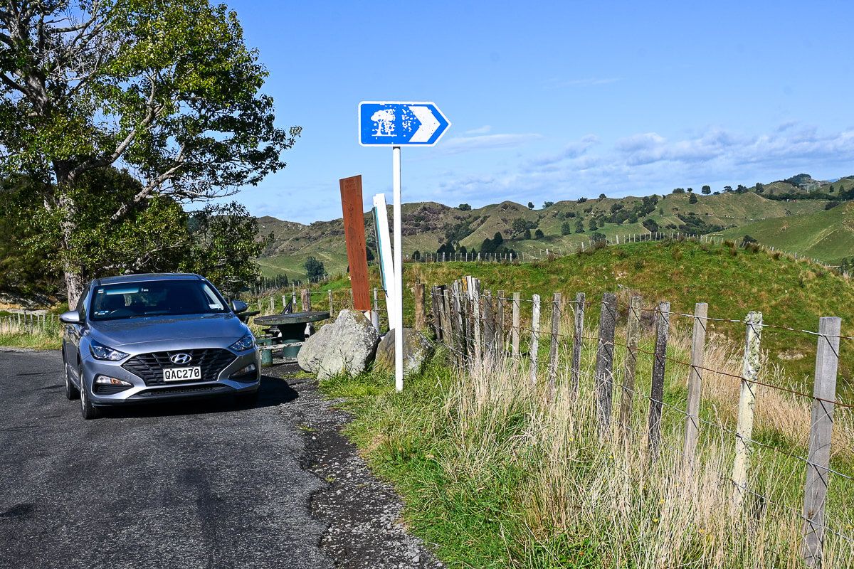Parkendes Auto am Wegesrand vor grüner Hügellandschaft