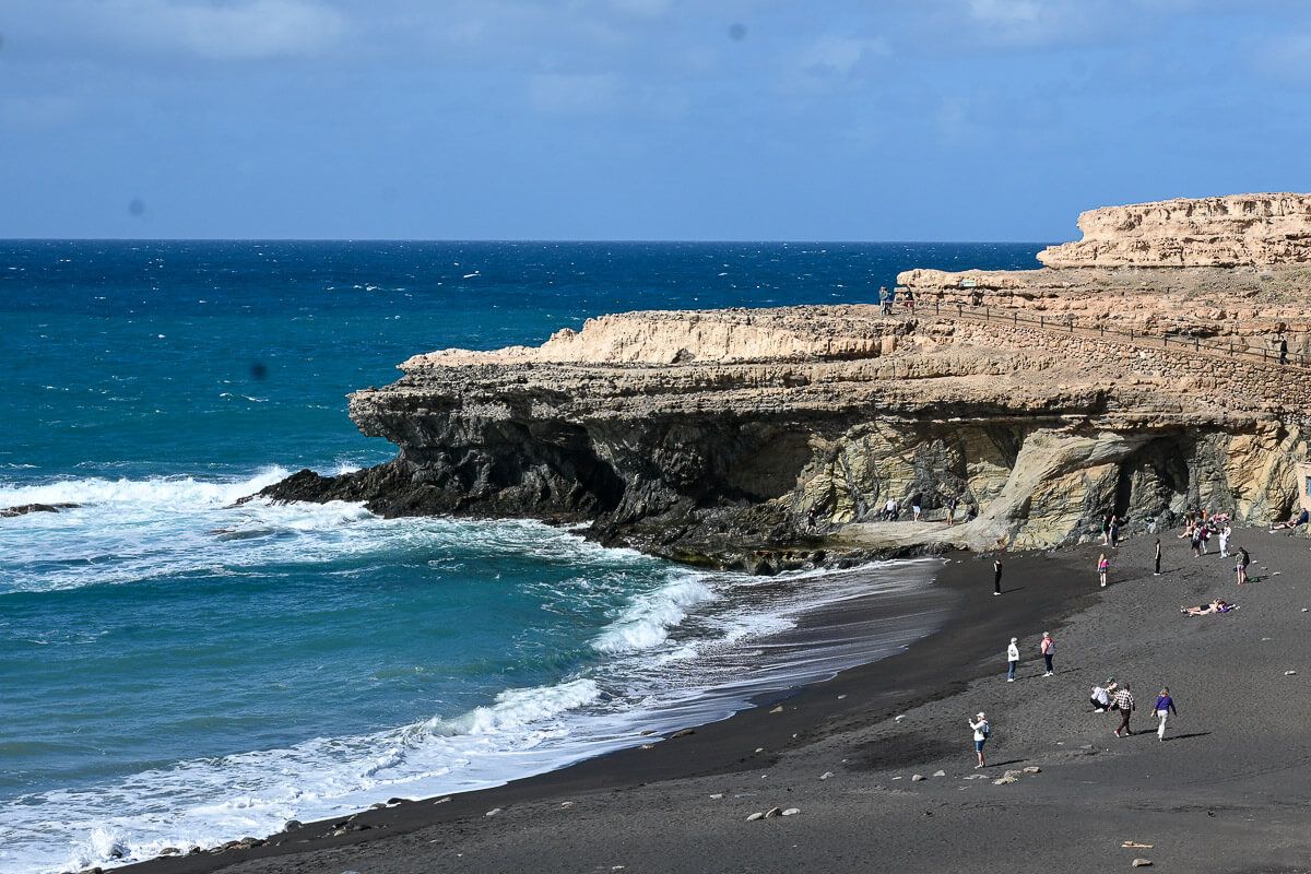 Wilder Strand mit wenigen Menschen, eingerahmt von Felsen