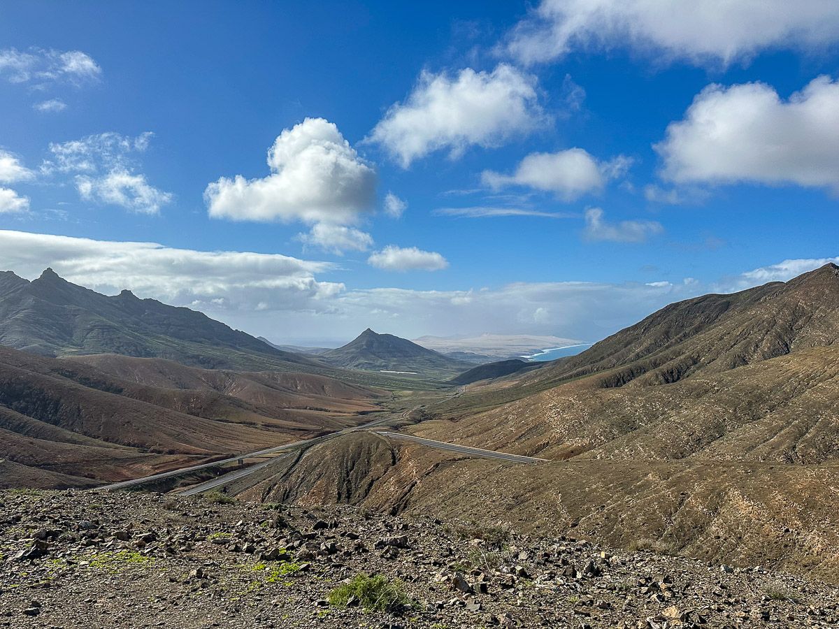 Aussichtspunkt mit Blick ins Bergland; im Hintergrund ein Strand