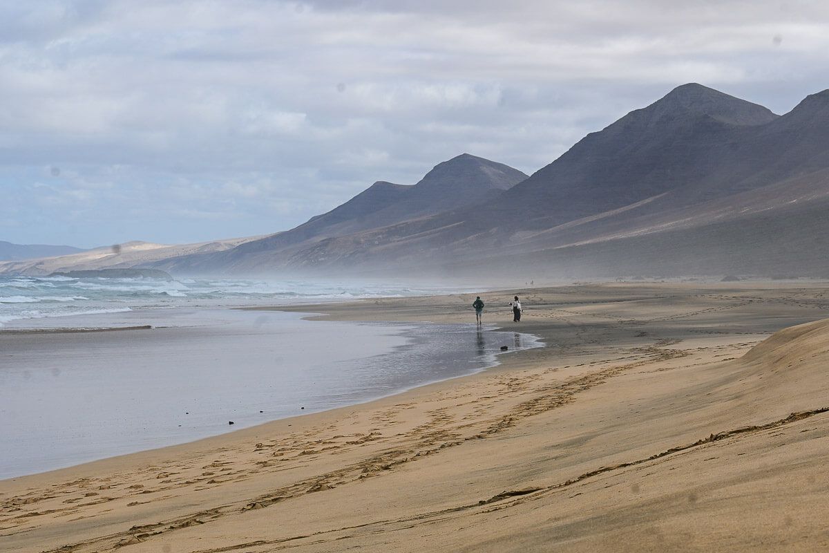 wilder Strand mit zwei Spaziergängern
