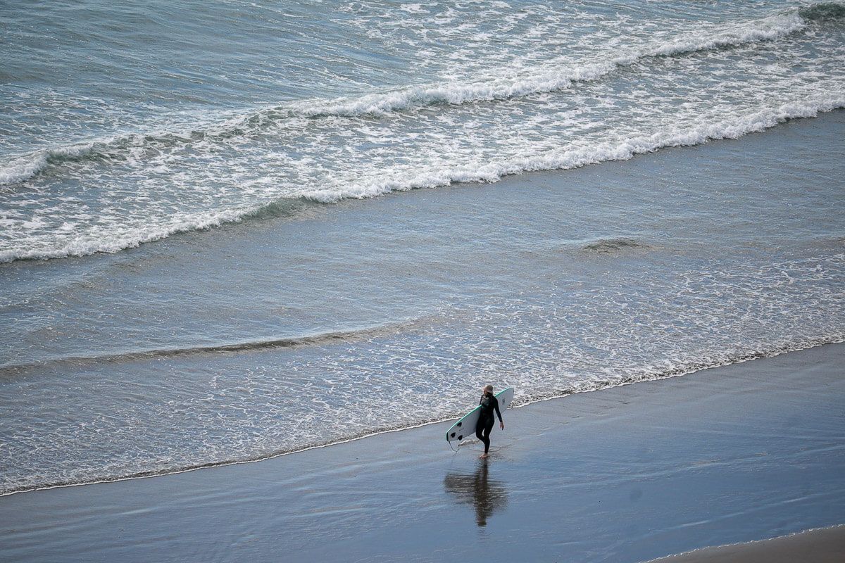 Surfer mit Brett am Ngarunui Beach 