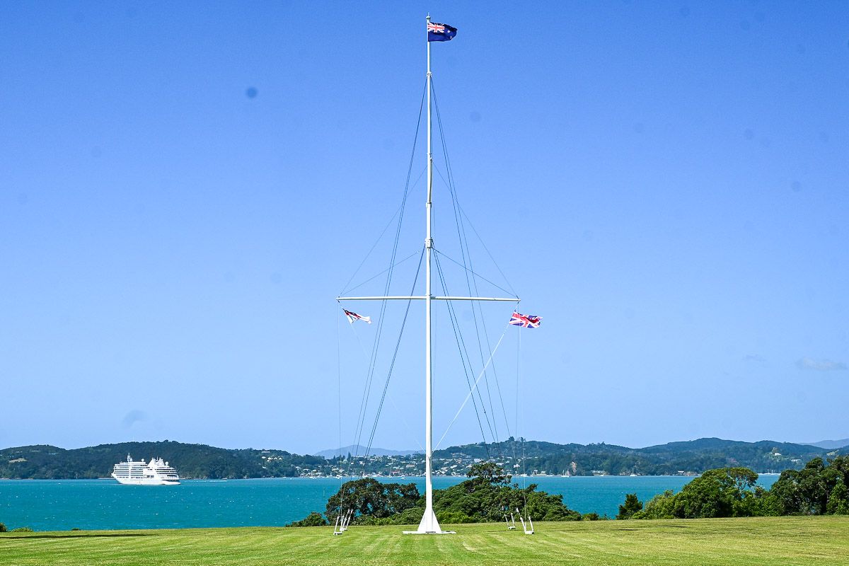Northland Neuseeland: Waitangi Treaty Grounds. Fahnenstange mit drei Flaggen vor der Bay of Islands