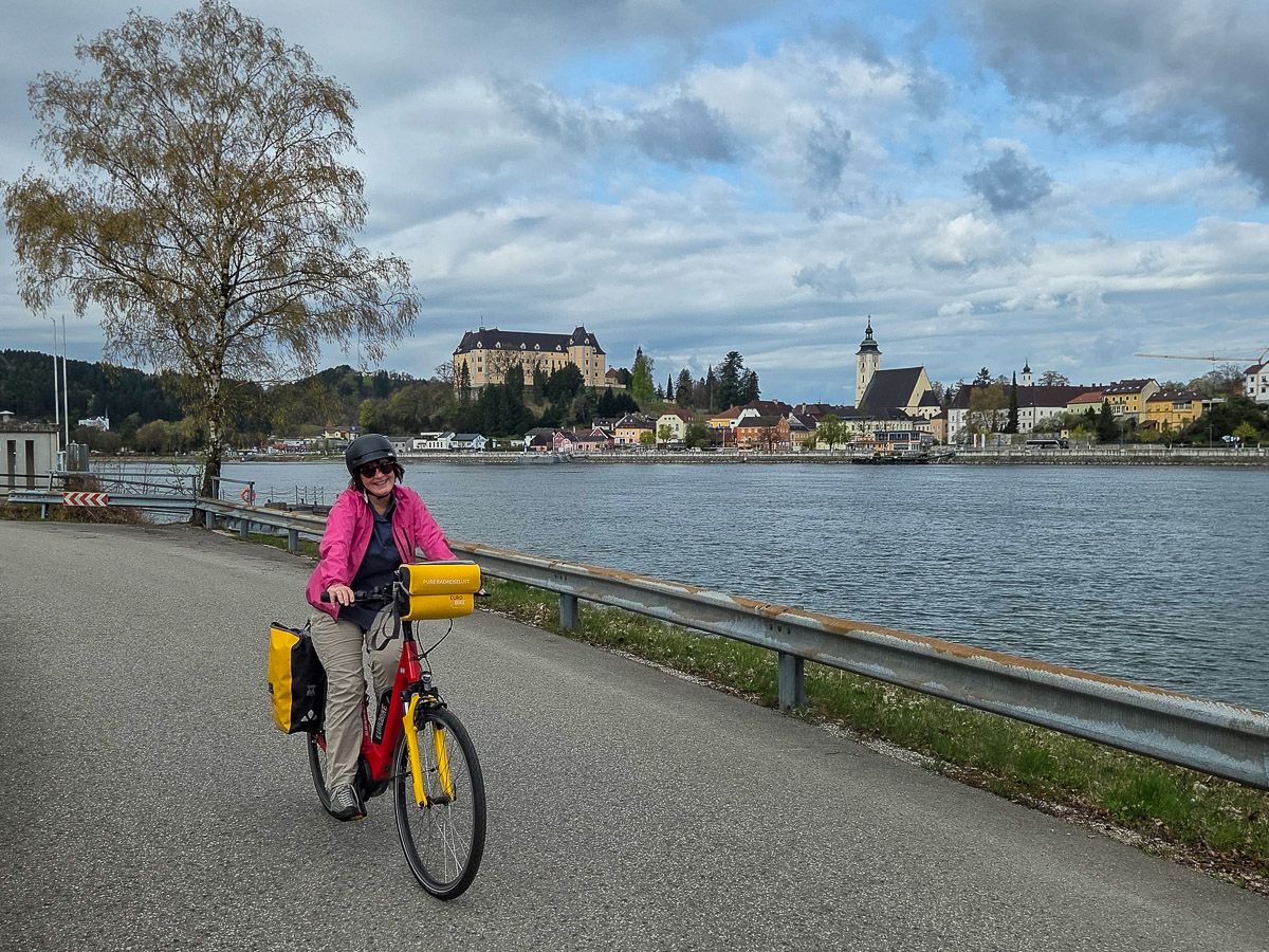 Radlerin auf dem Donauradweg vor der Kulisse von Grein