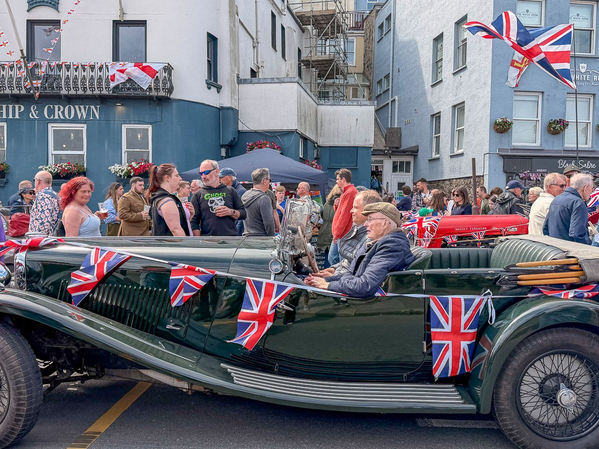 Oldtimer mit britischen Flaggen inmitten einer Menschenmasse