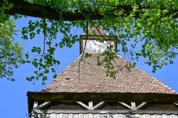 Uhrturm aus Holz, umrahmt von Blättern