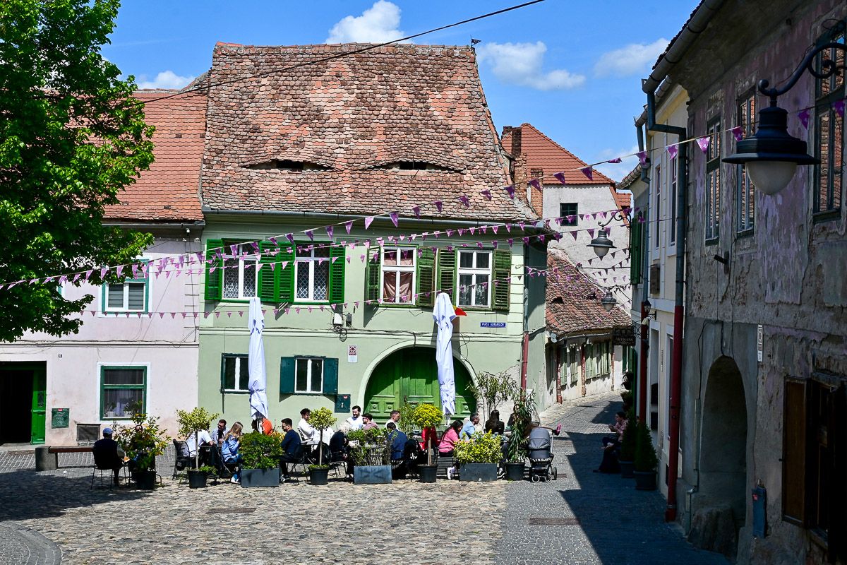 Fingerlingsplatz mit Cafeterrasse und grünem Haus mit Dachaugen