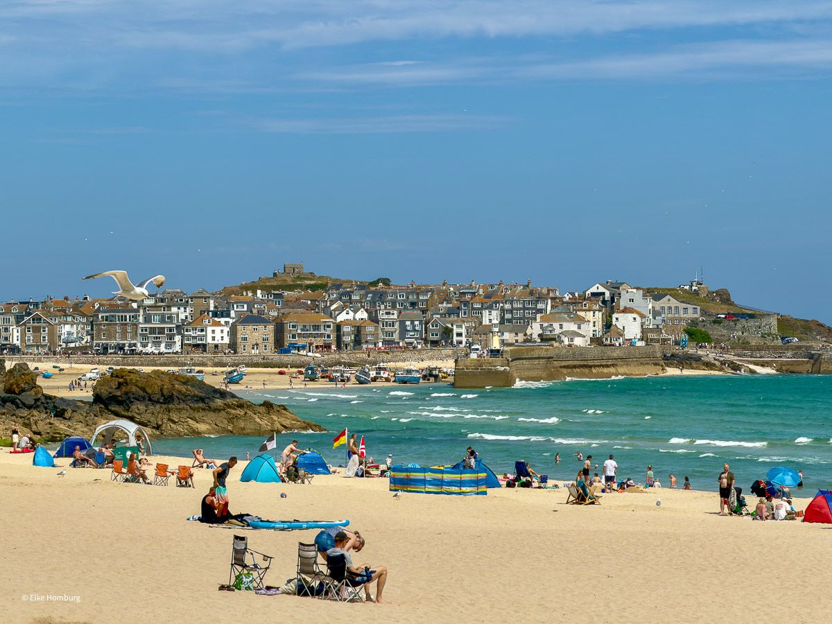 Heller Sandstrand mit Badenden und Blick auf den Hafen von St. Ives
