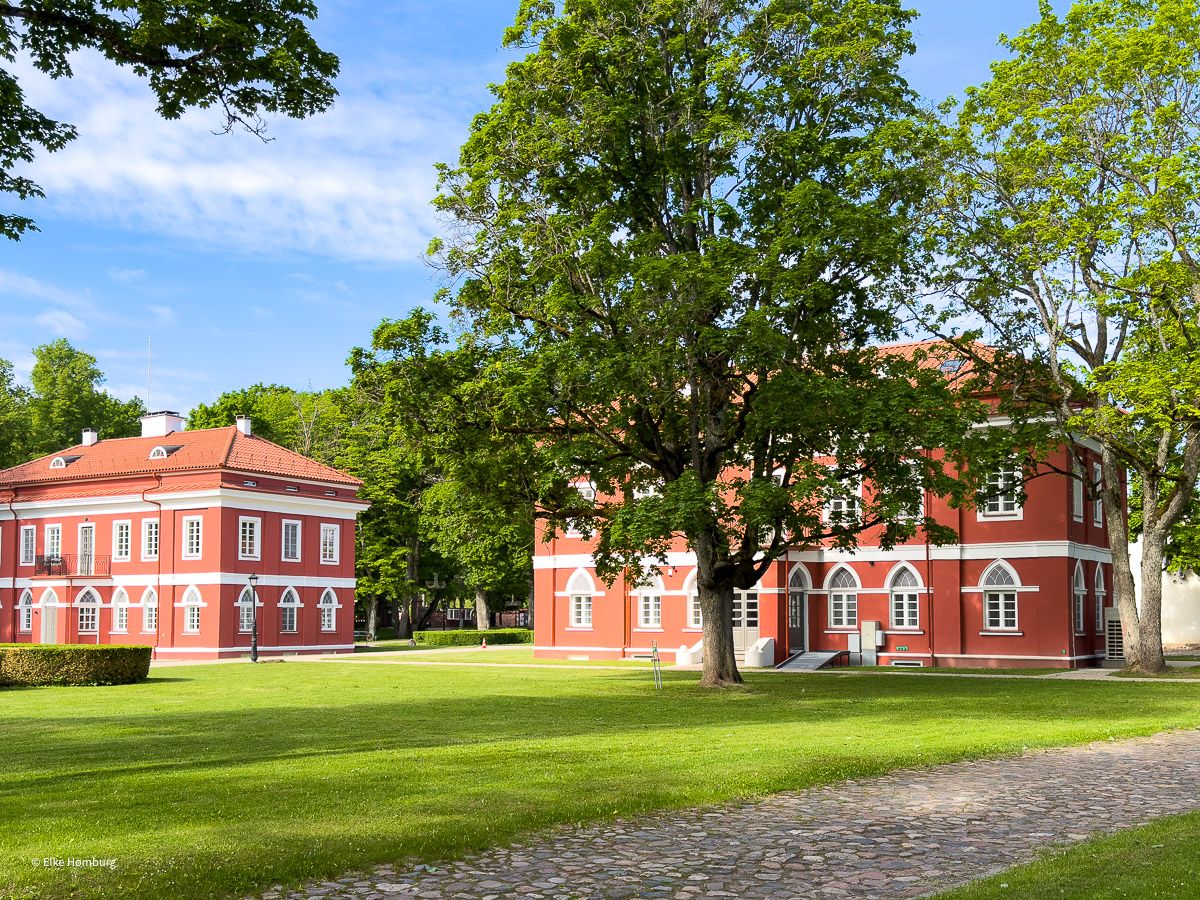 Gebäude eines Herrenhauses in Rot inmitten einen Parks