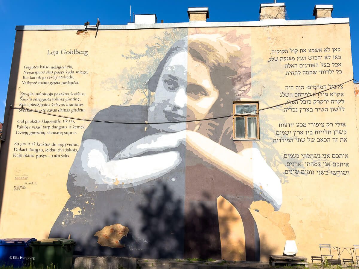 Riesiges Wandbild, das eine junge Frau und Gedichtzeilen in Litauisch und Hebräisch zeigt