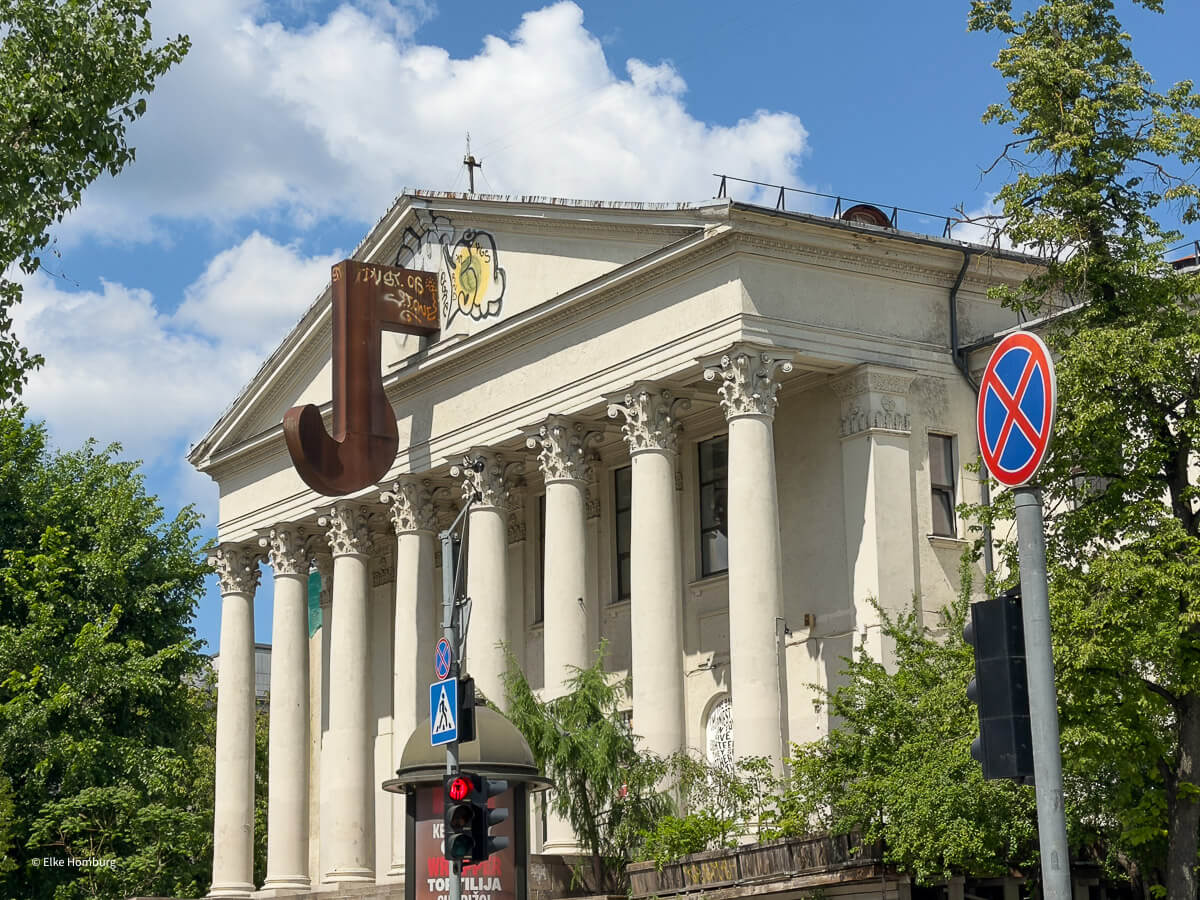 Klassizistisches Gebäude mit Säulen und einem riesigen, rostigen Eisenhaken