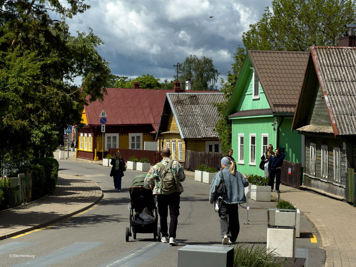 Straße mit bunten Holzhäusern auf der eine Familie spazierengeht
