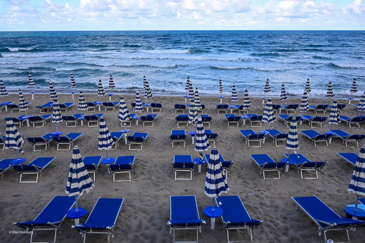 Blaue Sonnenliegen am Strand und das Meer