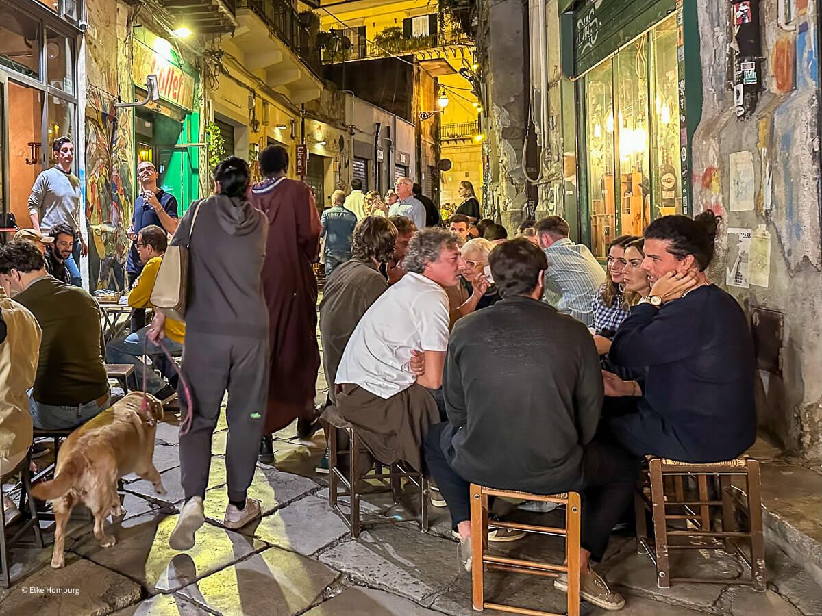 Feiernde Menschen in einer Straße mit vielen Bars