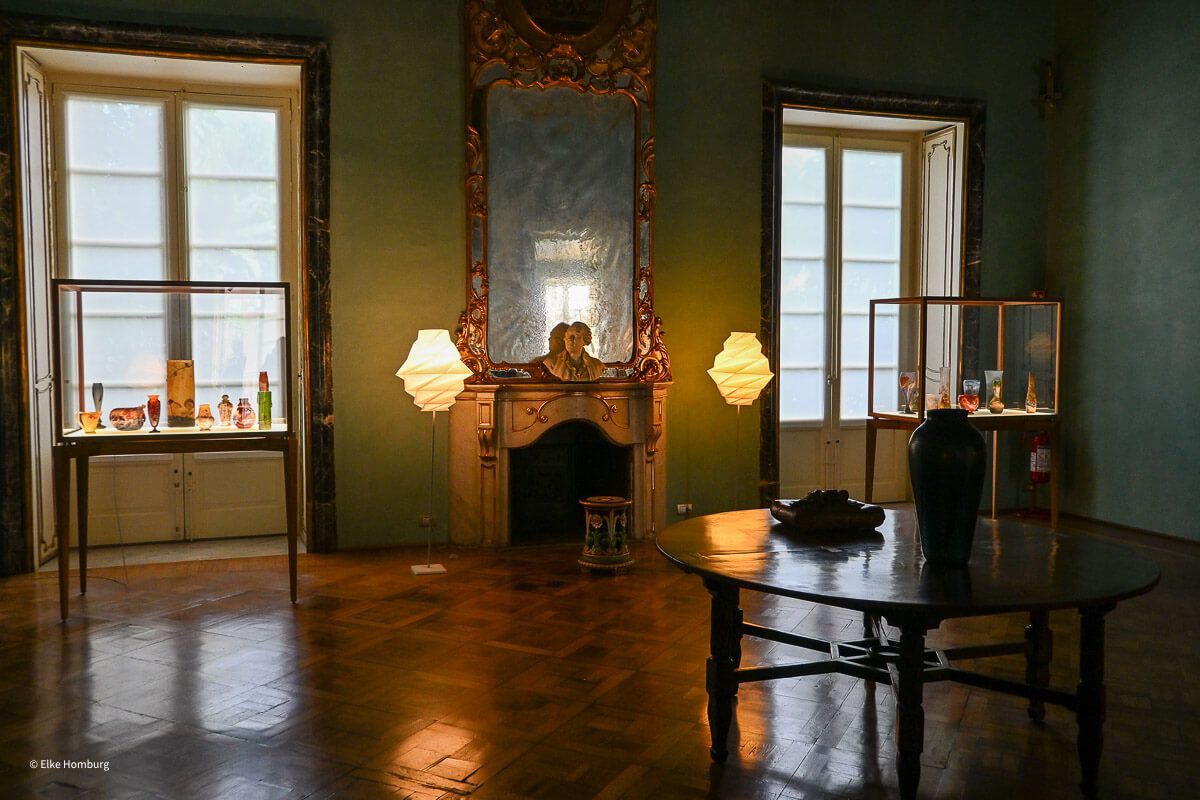 Raum eines Palazzo mit Spiegel und Vitrinen