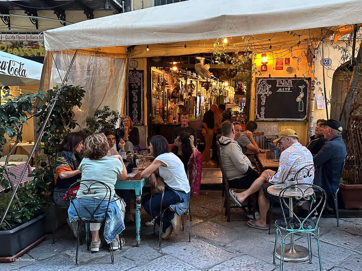 Bar mit vielen Gästen an zwei Tischen vor der Tür