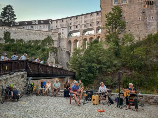 Blick auf die mehrstöckige Mantelbrücke; im Vordergrund Musiker
