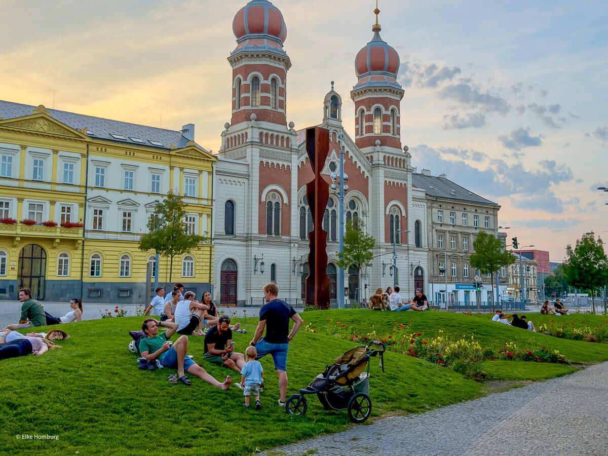 Viel mehr als eine Bierstadt: ein Wochenende in Pilsen 34 Synagoge mit zwei Zwiebeltürmen. Auf den Rasen davor sitzen viele Menschen.